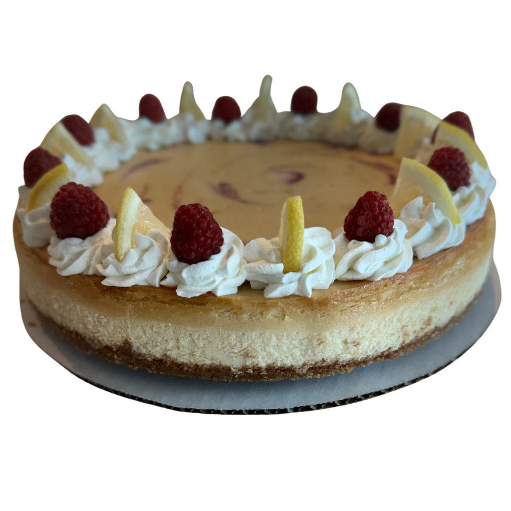Whole lemon raspberry cheesecake with cream rosettes, fresh raspberries, lemon slices and white chocolate shards