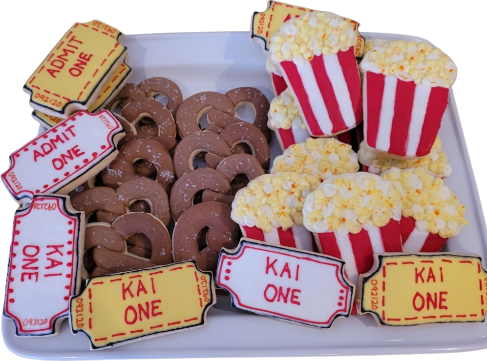 Movie night cookies with admit one tickets, popcorn boxes and pretzels on a tray